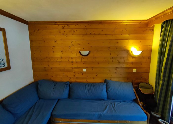Le salon d'un meublé touristique avec canapé d'angle et lambris avant un home staging