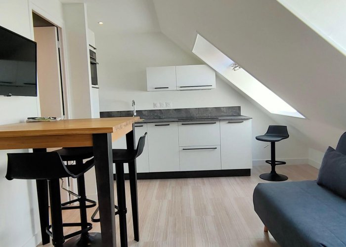 renovation-amenagement-comble-apres Un appartement sous les combles avec une cuisine intégrée et un coin salon après home staging